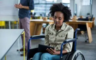 Young African American Woman in a wheelchair holding and browsing in her tablet about social security disability information