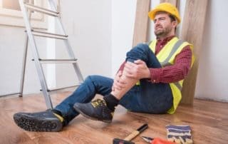 Injured worker at job site holding his knee in pain